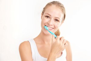 a blonde woman brushes her teeth